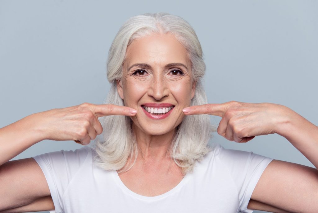 mature woman pointing to her smile